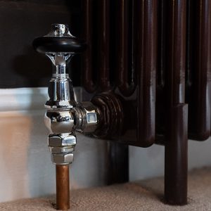 Close up of traditional nickel manual valve with chocolate brown multi-column radiator